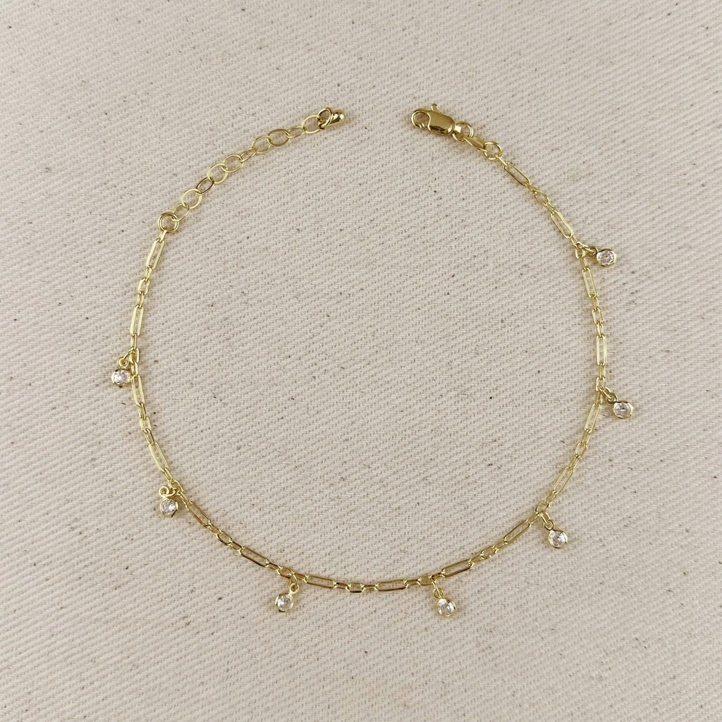 Gold anklet with small dangling charms on a beige fabric background at Shop Rutledge Exchange for curated vintage and jewelry in Camden, SC.&nbsp;